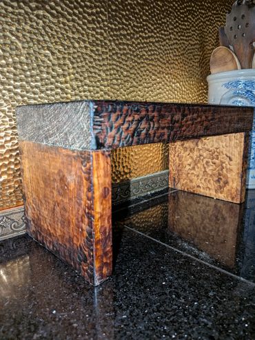 Handcrafted wooden stool with a textured finish on a kitchen countertop.