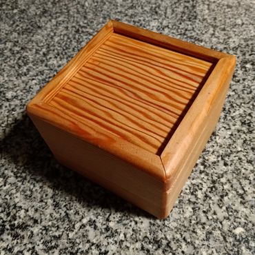 A small wooden box with a sliding lid on a granite surface.