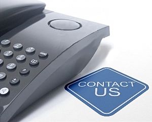 Black desk phone next to a blue diamond-shaped "Contact Us" sign.







