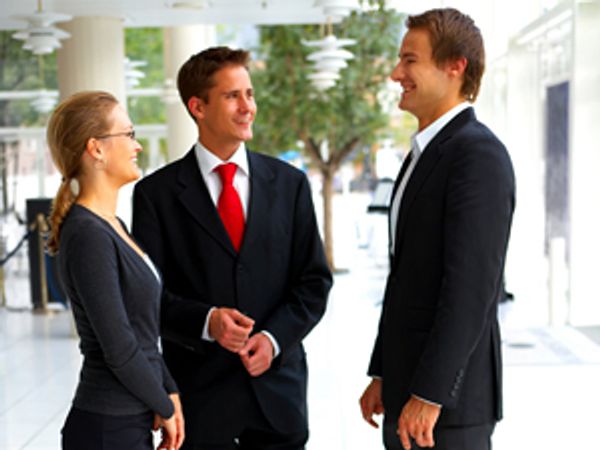 Three business people talking in an office building.