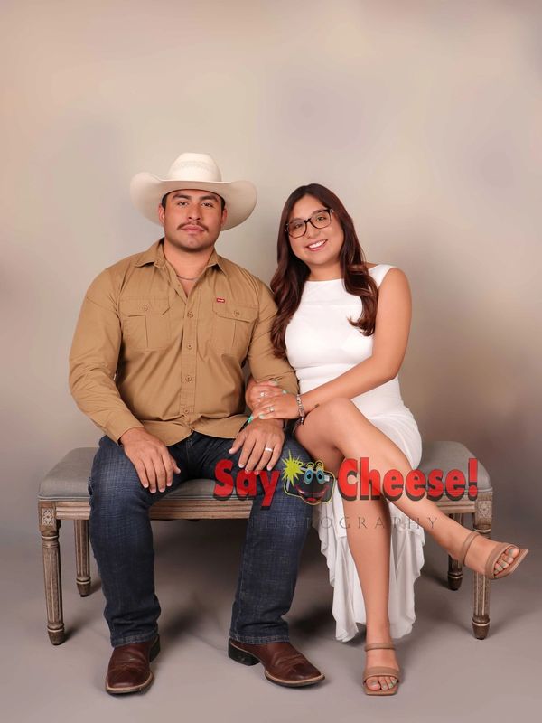 Couple sitting on a bench, smiling at the camera.