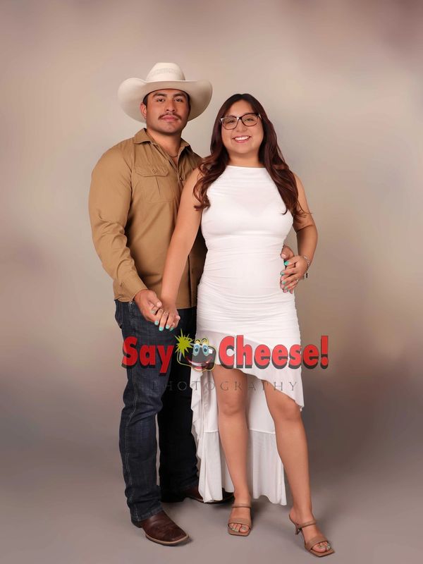 Couple posing for a photo with smiles, holding hands.