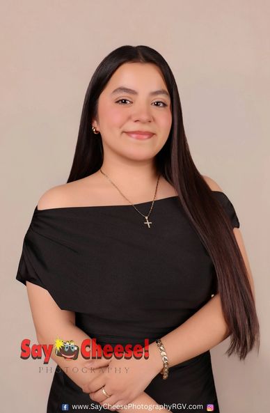 Young woman in black off-shoulder dress smiling against beige background.