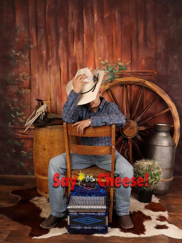 Boy in cowboy hat with accordion, rustic backdrop and vintage props.