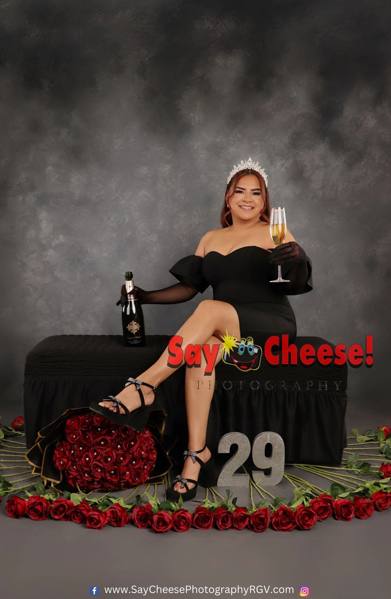 Woman in black dress celebrating 29th birthday with champagne and roses.