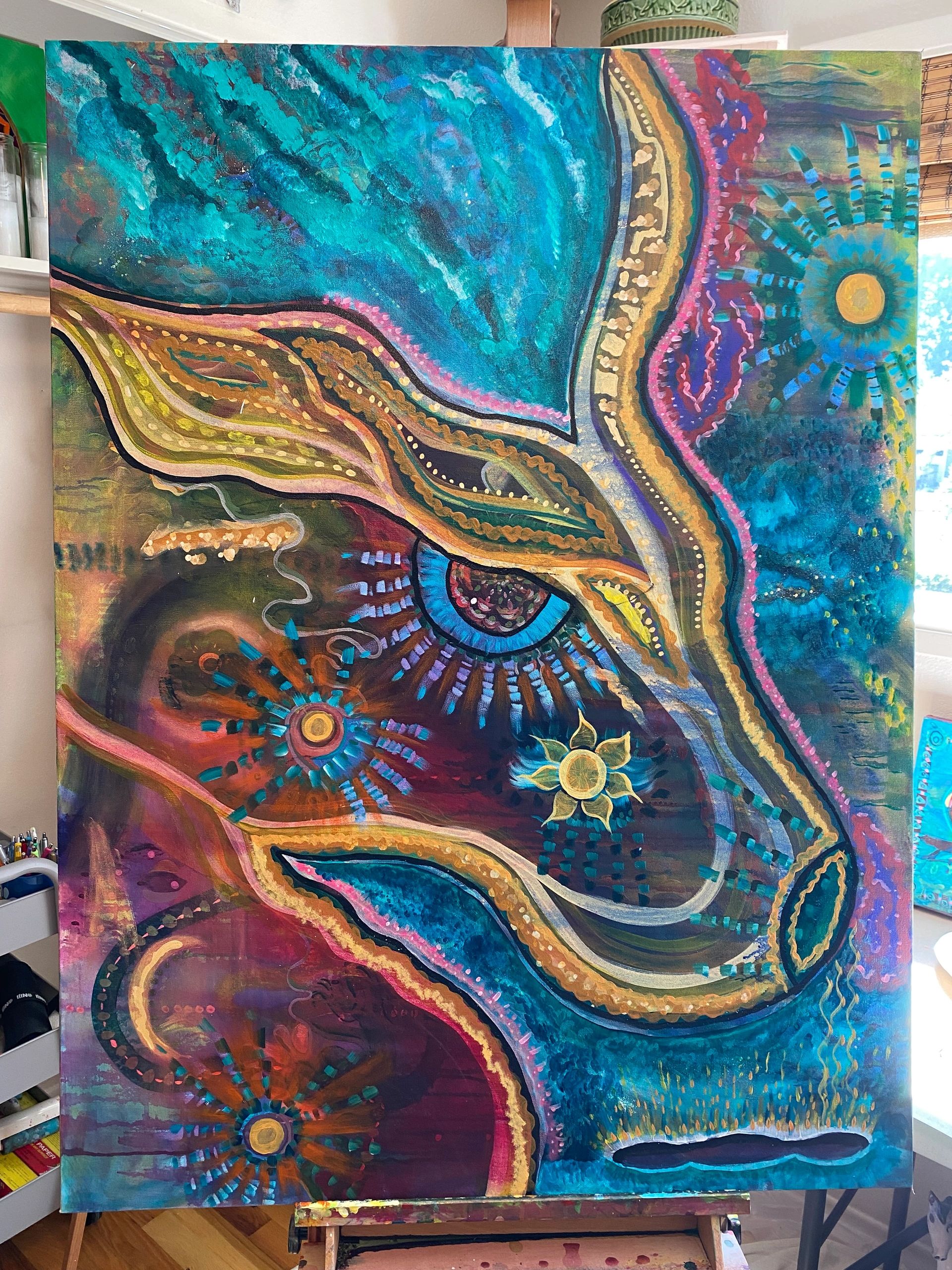 Colorful abstract painting featuring eye and floral motifs with vibrant blue and gold accents.