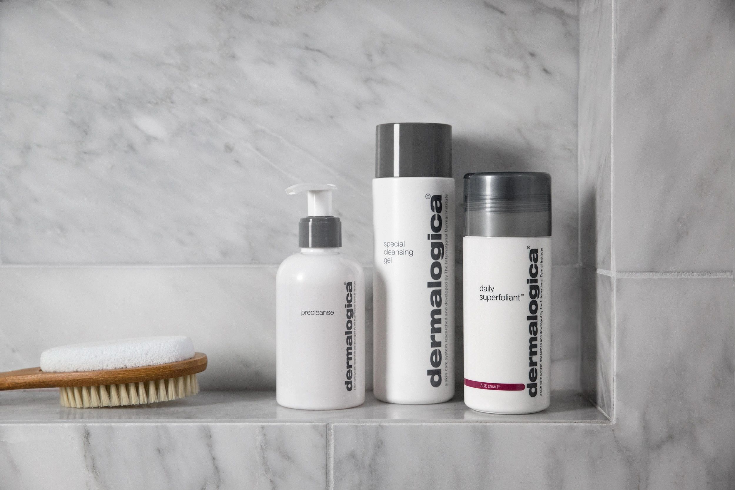 3 bottles Dermalogica skin care retail products on a shelf with a wooden body brush 