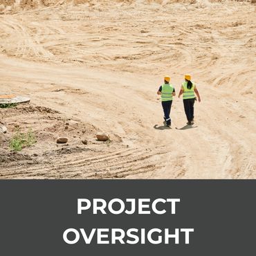 Two workers in safety vests and helmets walking on a construction site.