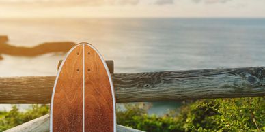Longboard leaning on wooden fence with ocean view.
