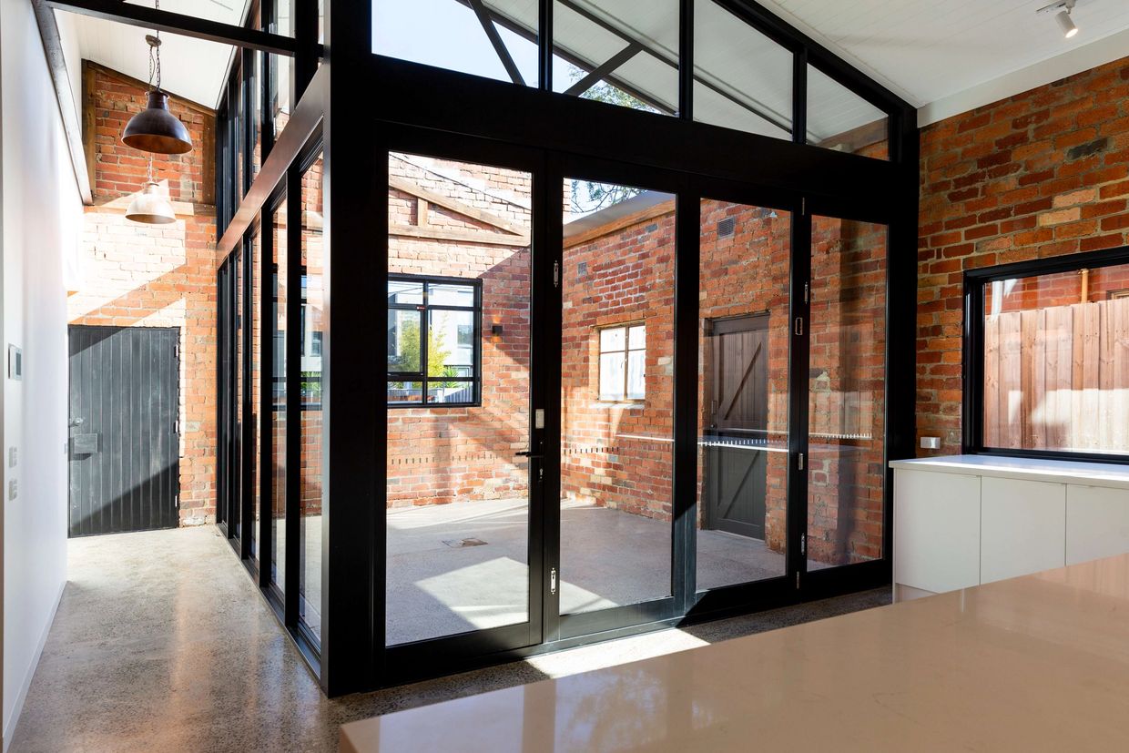 Outdoor courtyard framed by black metal sliding doors designed by Dana Meadows Architect