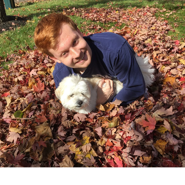 a boy with a dog is lying down on the leaves 