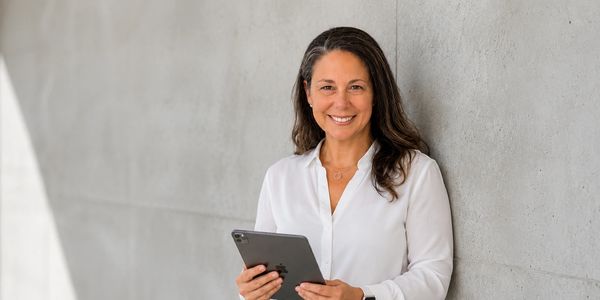 Woman smiling while holding a tablet.