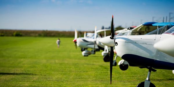 Small propeller airplanes lined up on a grassy airfield.