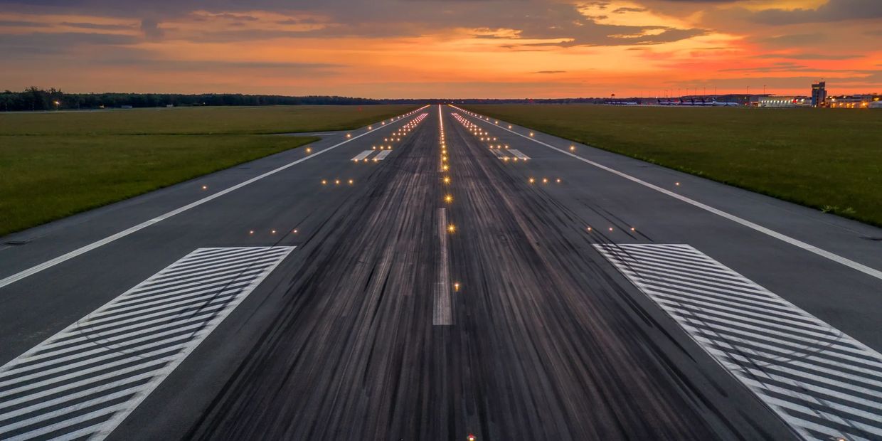 A runway at sunset with lights guiding the way.