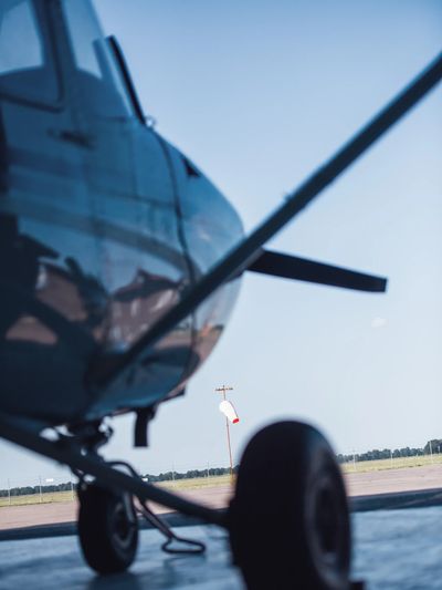 Close-up view of an airplane's landing gear and wing at an airfield.