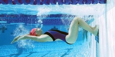 Swimmer pushing off the pool wall underwater in a streamlined position.