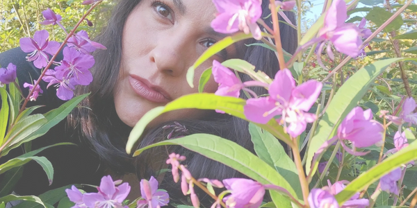 Chantal Rondeau with dark hair surrounded by vibrant fireweed flowers outdoors.