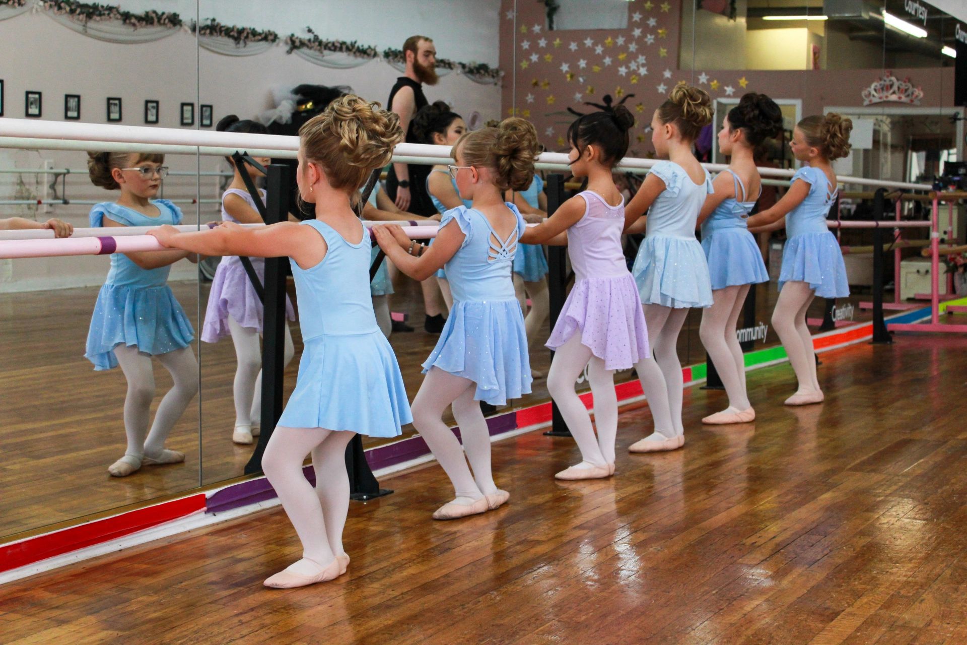 Young ballerinas practicing at the barre in a dance studio.