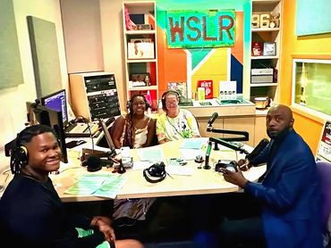 Four people in a colorful radio station studio with WSLR sign.