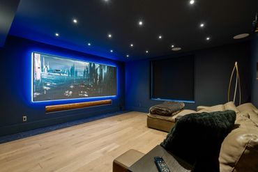 Modern home theater room with a large screen and cozy seating.