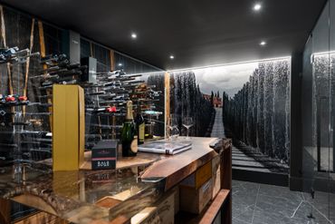 Elegant wine cellar with a modern tasting area and scenic mural.