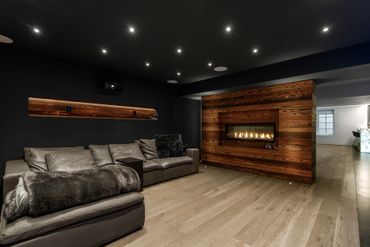 Modern living room with dark walls, leather sofa, and wooden accent fireplace.