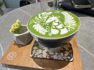 Artistic matcha latte with intricate unicorn and leaf design.