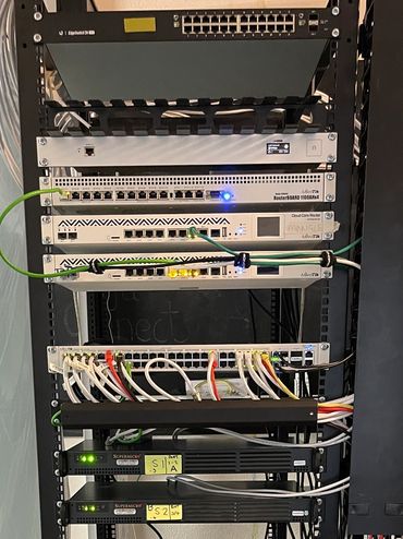 A server rack with various networking and computing devices connected by cables.