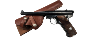 A vintage black pistol with wooden grips and a brown leather holster.