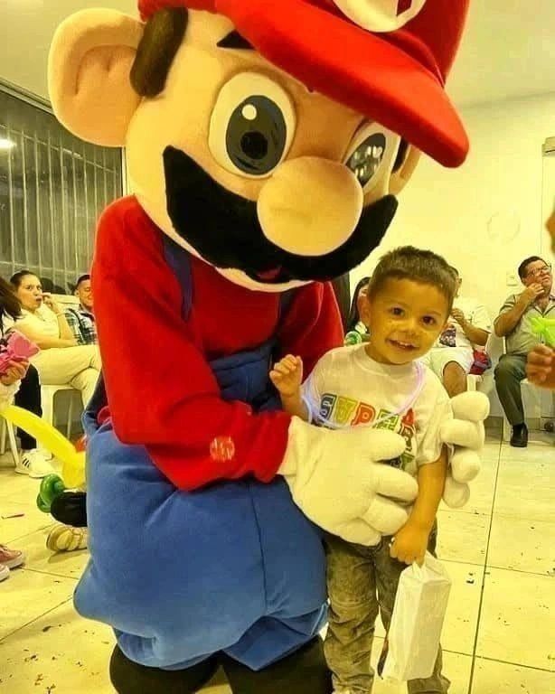 Niño sonriente con personaje de disfraz de Mario Bros.