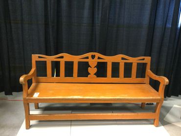 Wooden bench with decorative backrest against black curtains.
