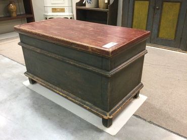 Vintage wooden storage chest with a dark base and reddish top.
