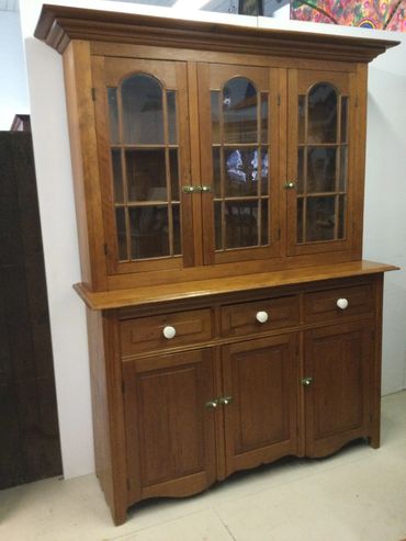 Wooden cabinet with glass doors and multiple storage compartments.