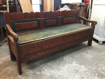 Antique wooden bench with storage and decorative carvings.