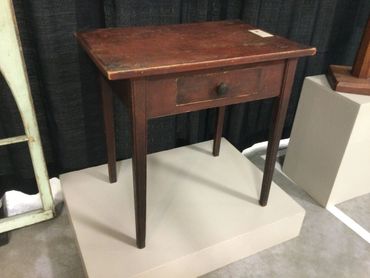 Vintage wooden side table with a single drawer and tapered legs.