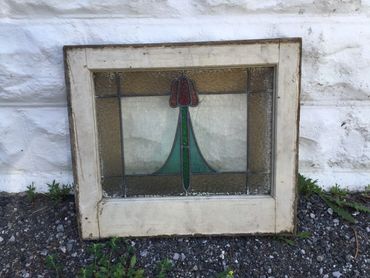 Vintage stained glass window with floral design in a wooden frame.