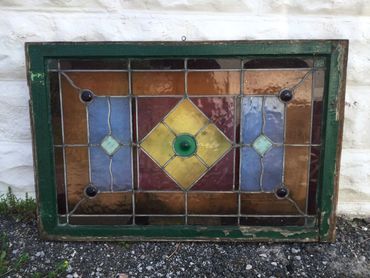 A stained glass window with geometric patterns and a green frame.
