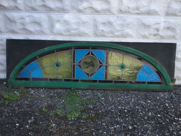 Arched stained glass window with geometric patterns in green, blue, and yellow.