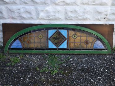 Arched stained glass window with geometric and floral patterns.