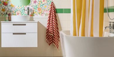 Bright bathroom with floral wallpaper, white vanity, and yellow-striped shower curtain.