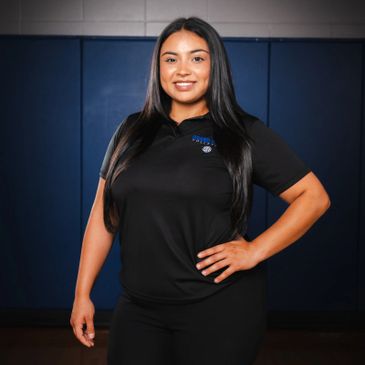Young woman confidently posing in a black polo shirt indoors.