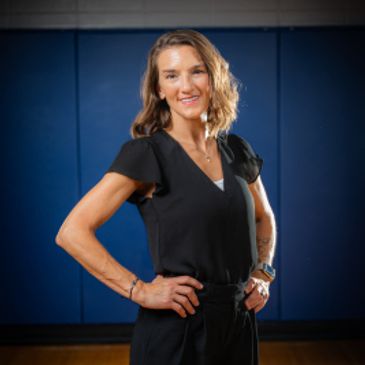 Confident woman posing with hands on hips in a gymnasium.