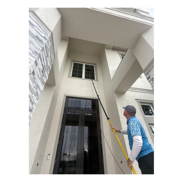 Man cleaning or repairing high window with a pole.