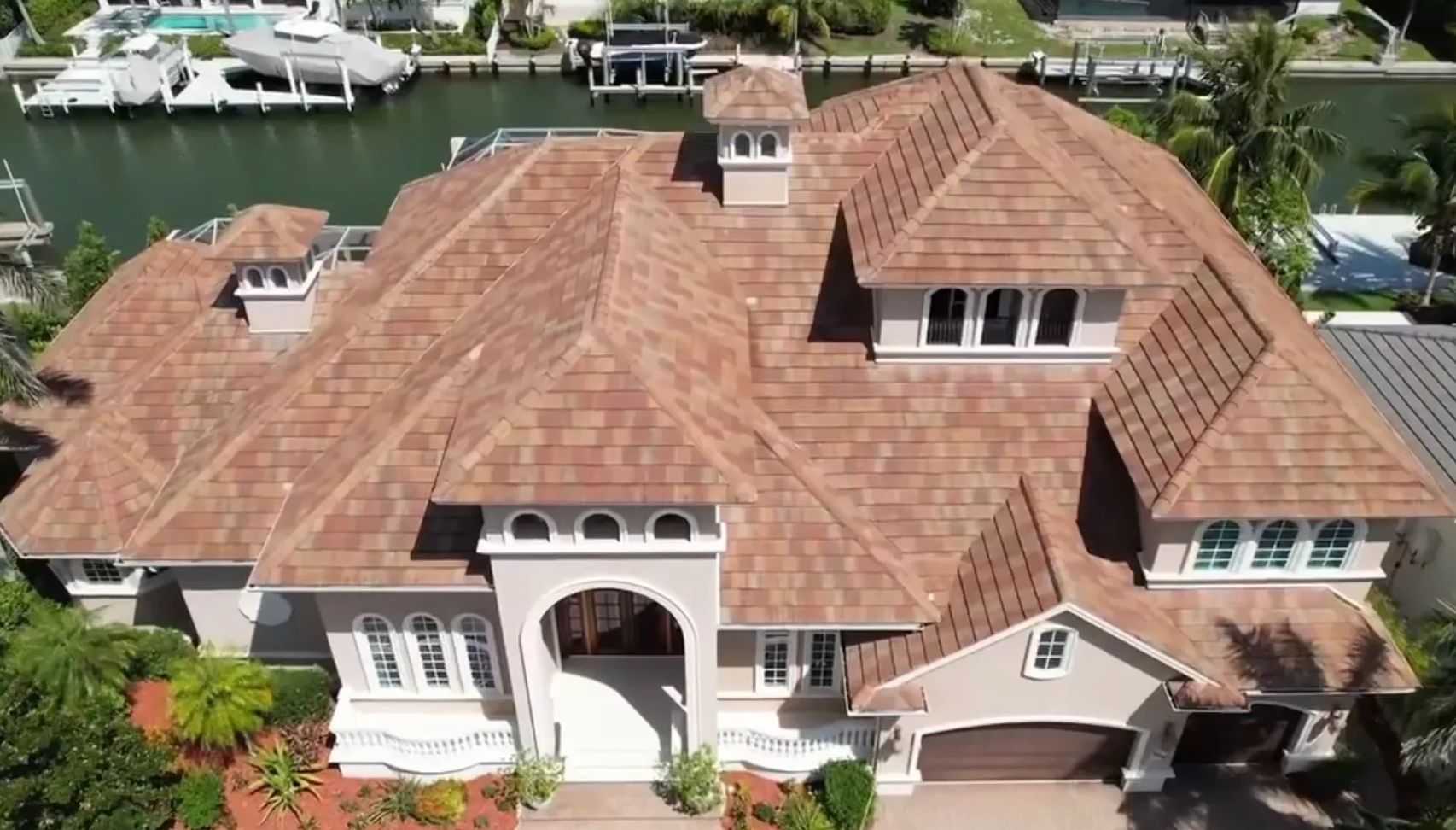 Large house with tile roof by the water.