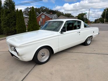 A classic white vintage car parked on a driveway.