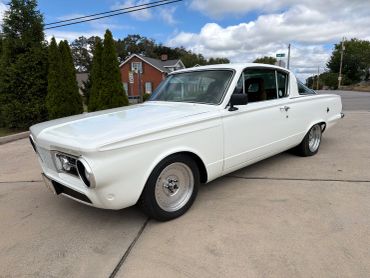 White vintage car parked on a driveway.