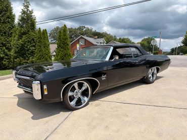 A shiny black vintage car parked on a driveway.