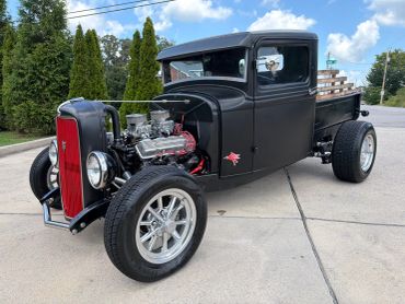 Classic black hot rod truck with exposed engine and wooden bed.