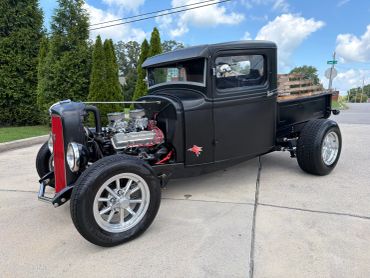 Custom black vintage hot rod truck with exposed engine.