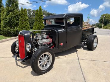Classic black hot rod with exposed engine and wooden bed.